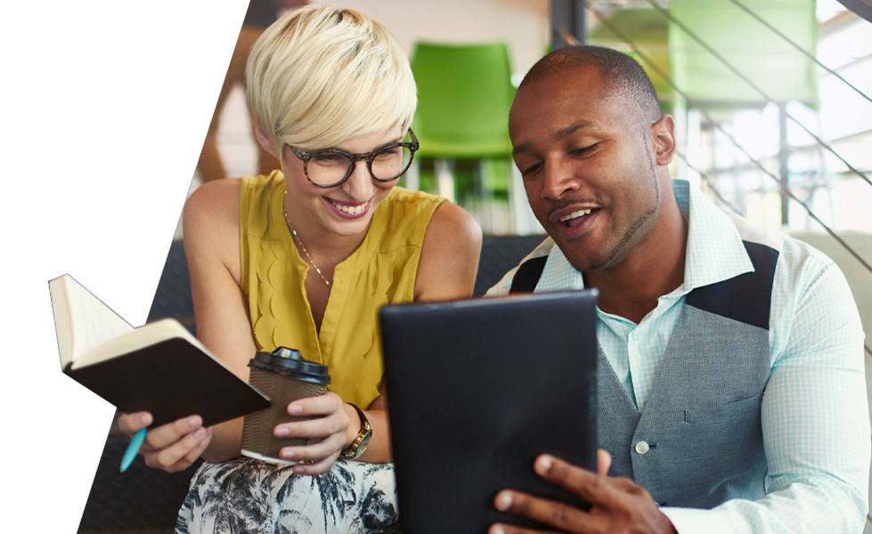 Two people sitting next to each other looking at tablet